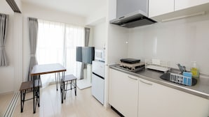 A modern kitchen with white cabinets, a built-in microwave, a stove, and a dining area with a table and chairs. - Shrine Side Kego Forest (Fukuoka City Chuoku Kego)