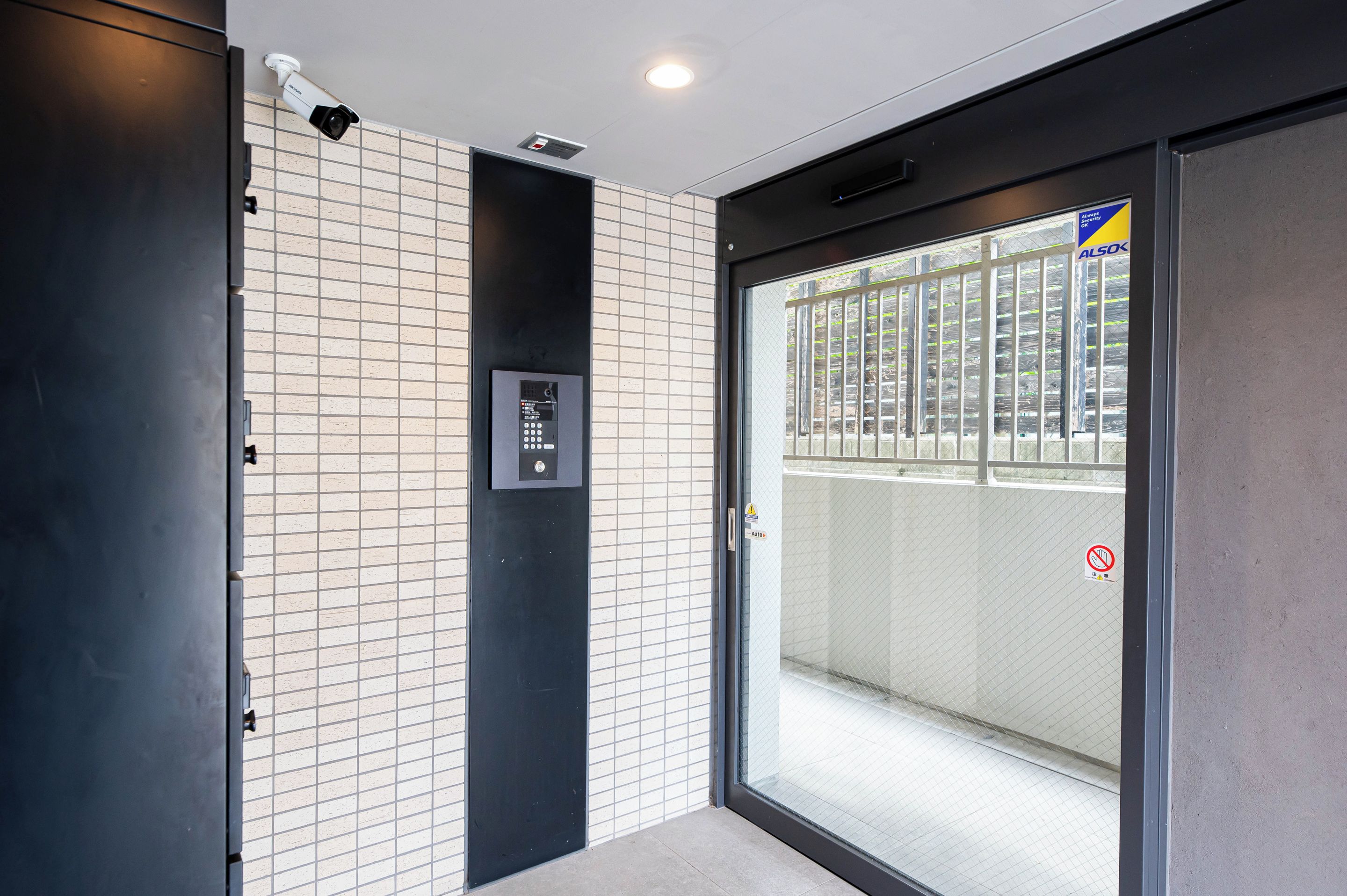A modern elevator with a control panel and a security camera above it.