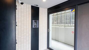A modern elevator with a control panel and a security camera above it.