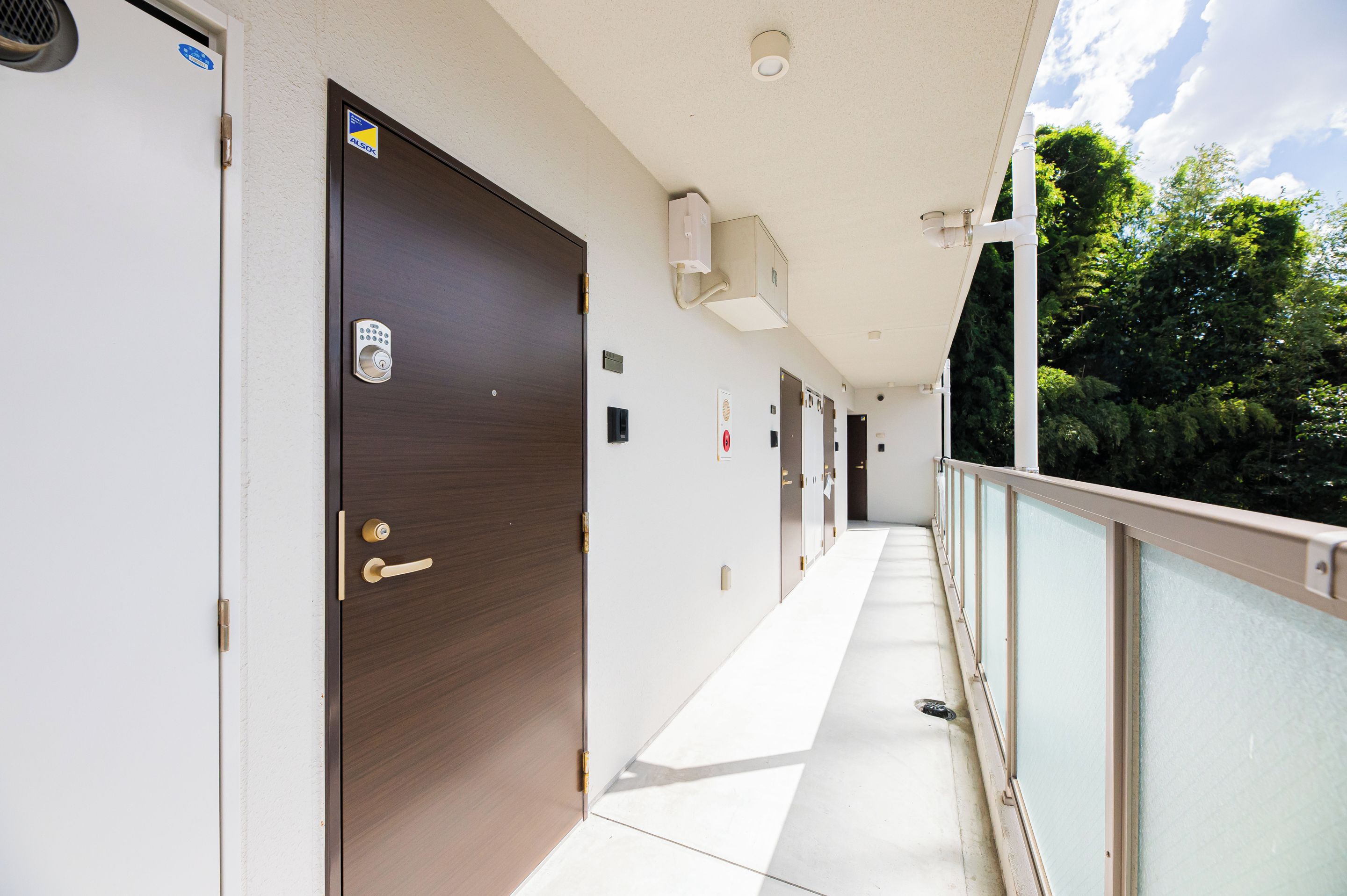 A corridor with doors, a security camera, and a balcony with a railing.