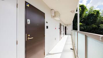 A corridor with doors, a security camera, and a balcony with a railing.