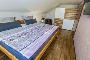 A bedroom with a bed, pillows, a chair, a nightstand, and a television. - Holiday apartment in Königheim with barbecue (Königheim)