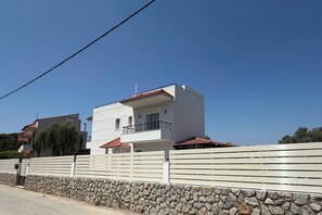 A modern two-story building with a stone wall and a metal fence in front. - Villa Yasmina (Ialisos)