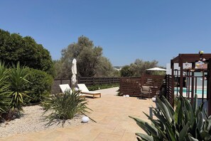 A patio area with lounge chairs, a pool, and a wooden pergola. - Villa Yasmina (Ialisos)