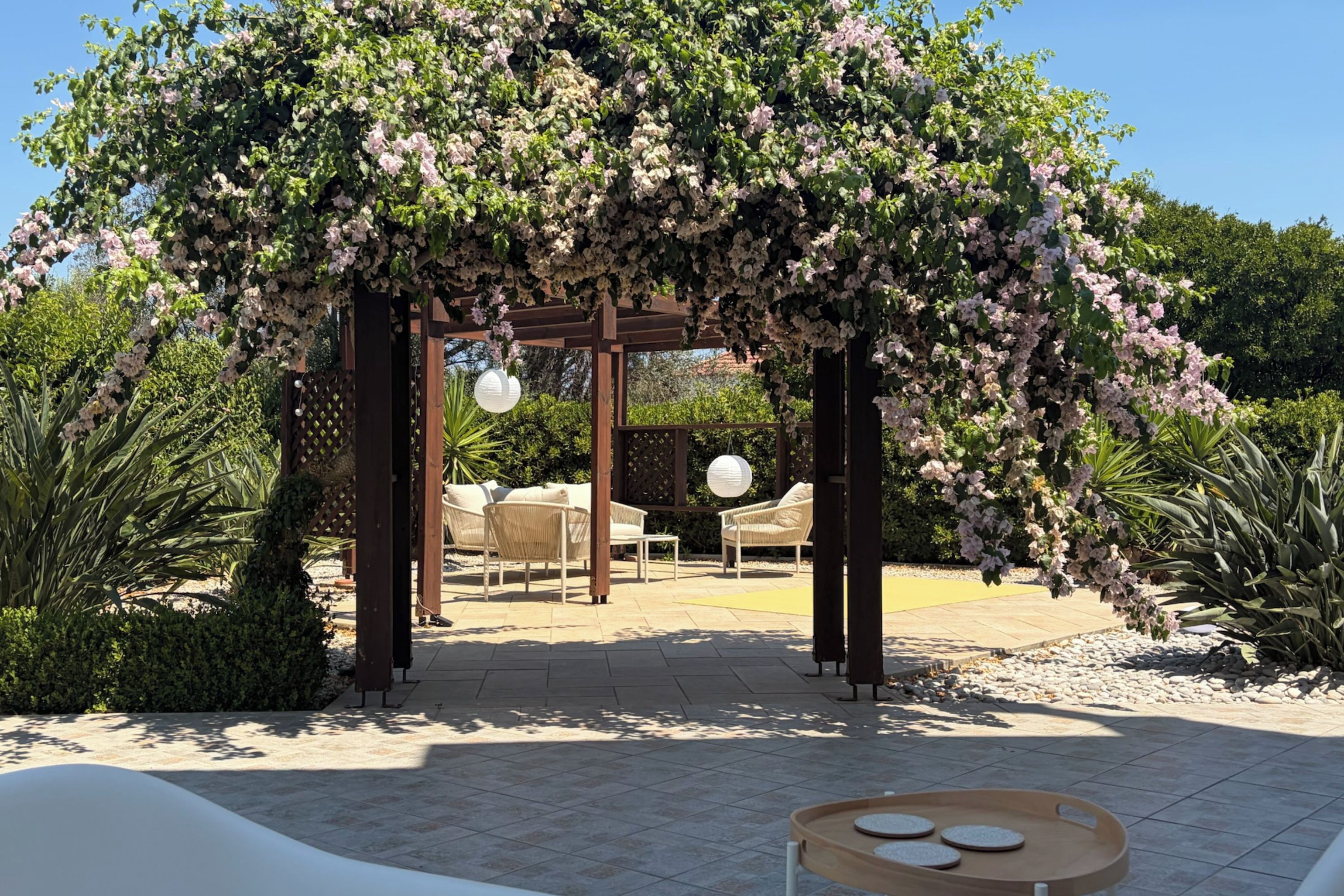 Un espace extérieur aménagé avec une pergola, des chaises et une table ronde, le tout abrité.