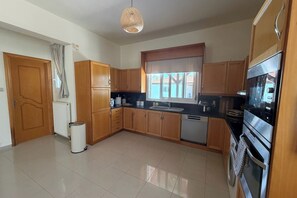 Una cocina con armarios de madera, horno de acero inoxidable y una ventana con cortinas.