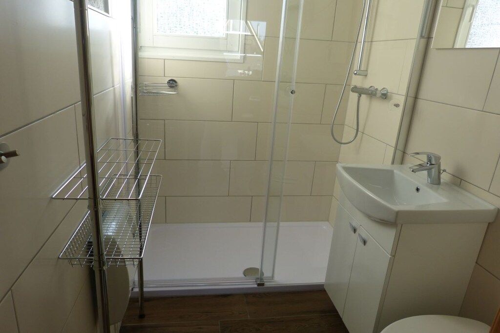 A small bathroom with a shower, a sink, and a toilet.