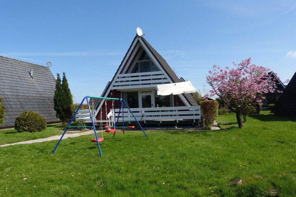 Ein Haus mit einem Satteldach, einer Schaukel und einer Kirschblüte.