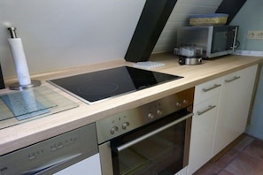 A kitchen with a built-in induction cooktop, a microwave, a toaster, and a dishwasher. - Holiday home with 2 bedrooms (Butjadingen)