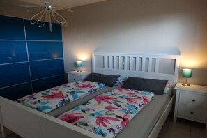 Une chambre à coucher avec un lit, deux tables de chevet et un luminaire fixé au mur.