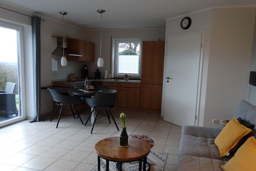 A compact living space with a dining area, kitchenette, and a sofa with cushions.