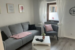 A modern living room with a grey sofa, a white coffee table, and a grey armchair. There are two framed motivational posters on the wall. - Holiday home with 2 bedrooms (Koblenz-Bassenheim)