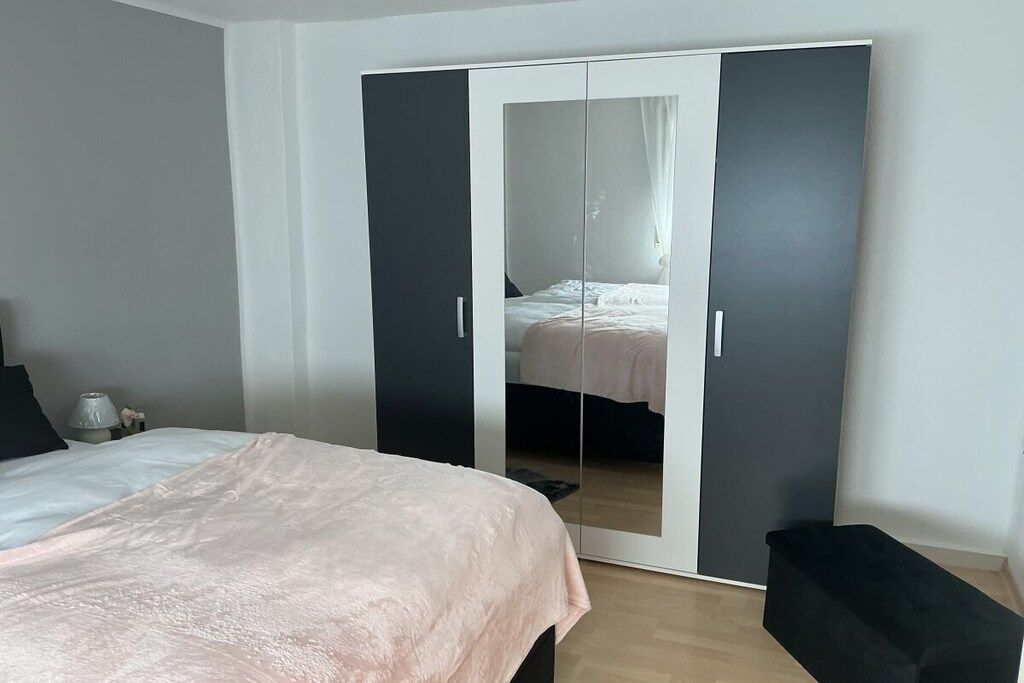 A bedroom with a bed, a wardrobe, and a bench.