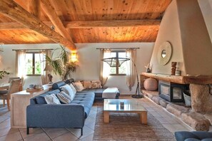 A cozy living room with a wooden ceiling, a blue sofa, a glass coffee table, and a fireplace. - Casa Nina Authentic Corsica house (Porto Vecchio)