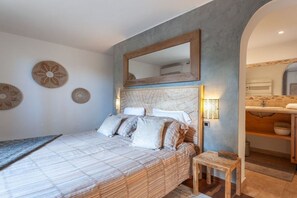 Une chambre à coucher comprenant un lit, une table de chevet, un miroir et des éléments décoratifs sur les murs.