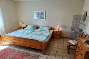 A bedroom with a wooden bed, bedside tables, a nightstand, a chair, a dresser, a mirror, and a bathroom with a sink and toilet. - Holiday apartment in Ulmen with swimming pool (Ulmen)