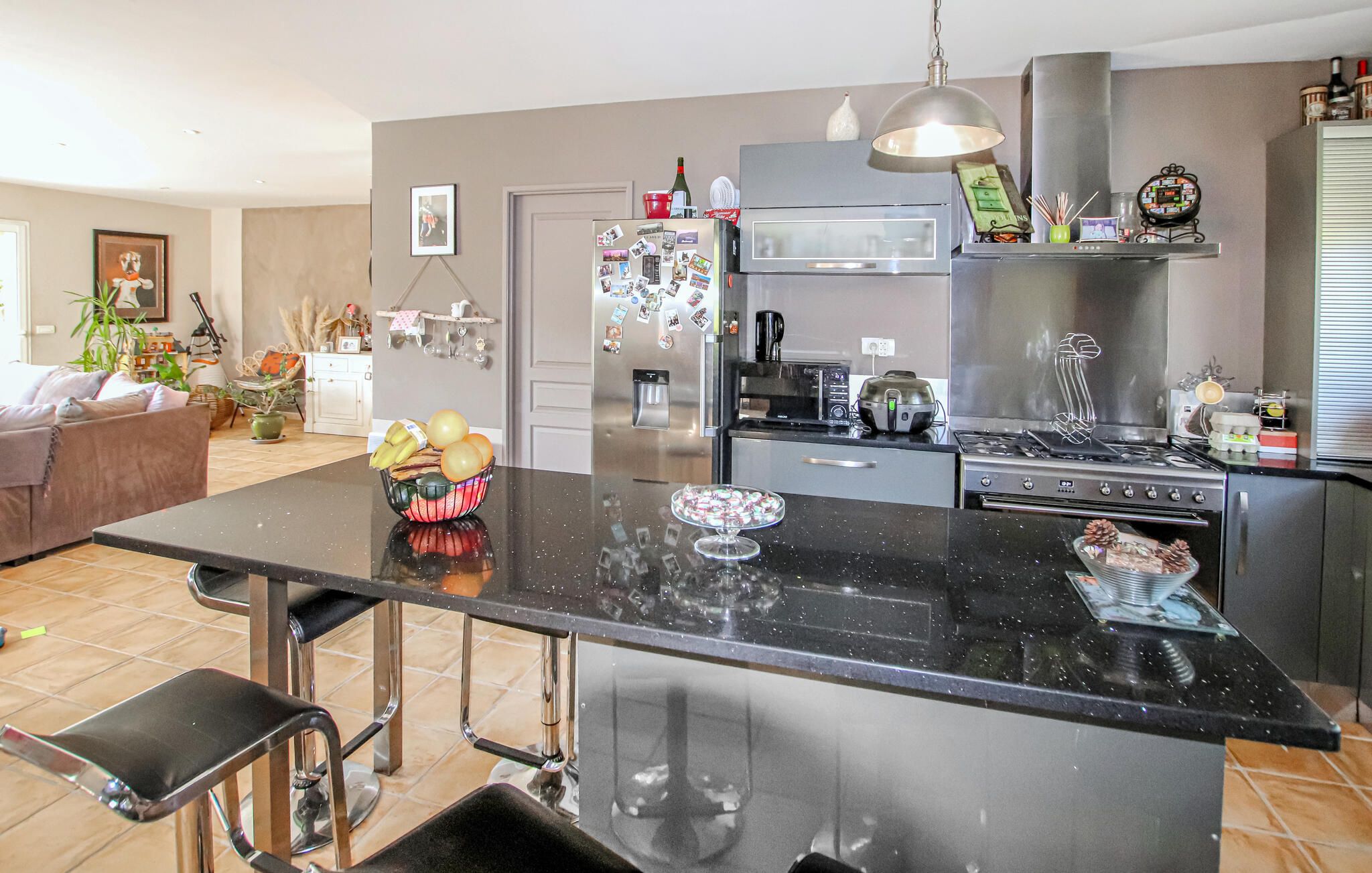 A modern kitchen with a central island, stainless steel appliances, and a dining area with a black countertop.