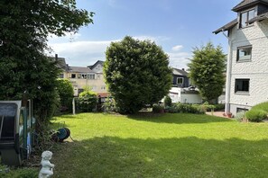 A residential area with a well-maintained lawn, a large tree, and houses with visible windows and balconies. - Holiday apartment with 2 bedrooms (Nieder-Olm)