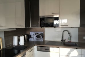 Ett modernt kök med vitvaror i rostfritt stål, en diskmaskin och en diskho.