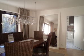 A dining area with a wooden table, wicker chairs, and a chandelier. - Holiday apartment with 2 bedrooms (Nieder-Olm)