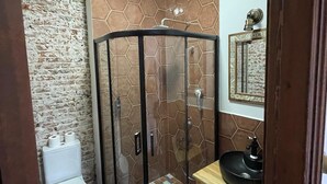 Ein Badezimmer mit Duschkabine aus Glas, Toilette und Waschbecken mit Holzplatte.