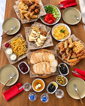 A table with various food items and condiments, including bread, cheese, and vegetables. - CUNDA KONAĞI (Ayvalik)