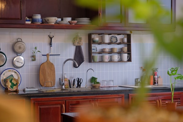 A kitchen with wooden cabinets, a tiled backsplash, and various kitchen utensils and dishes.