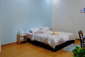 A bedroom with a single bed, a nightstand, a lamp, a chair, and a small table.