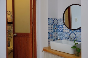 Un bagno con una porta in legno, un lavandino bianco e uno specchio.