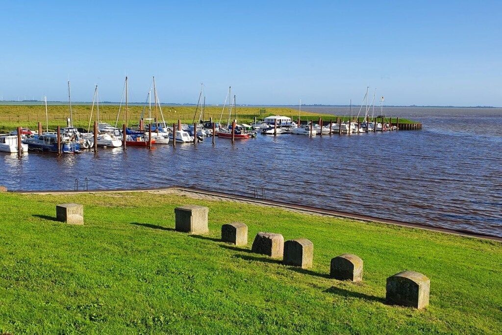 Een jachthaven met boten afgemeerd langs een groene oever.