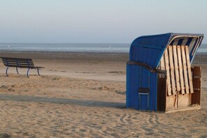 A beach with a wooden bench and a covered seating area. - Holiday home in Varel with swimming pool (Varel)