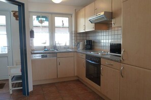 A kitchen with a dishwasher, oven, and a window with a view of a bird feeder. - Holiday home in Varel with swimming pool (Varel)
