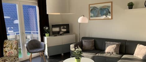 A modern living room with a sofa, armchair, and a round coffee table.