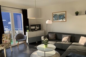 Een moderne zithoek met een bank, fauteuil en een rond salontafeltje.