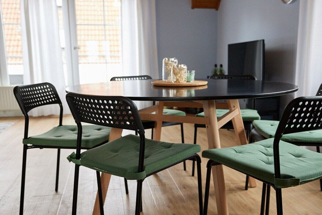 Un coin repas avec une table ronde, six chaises et un téléviseur en arrière-plan.