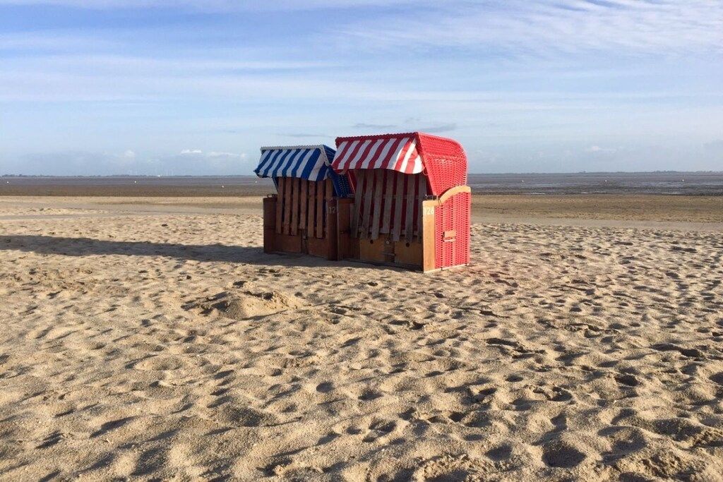 En strand med två små byggnader, troligen strandhytter, med randiga markiser.