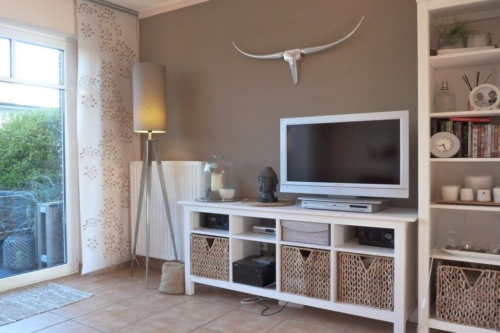 A living room with a TV, a lamp, and a bullhorn decoration on the wall.