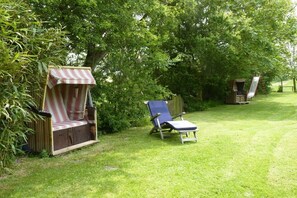 A grassy outdoor area with two lounge chairs and a small wooden structure. - Holiday home with 2 bedrooms (Osterhever)