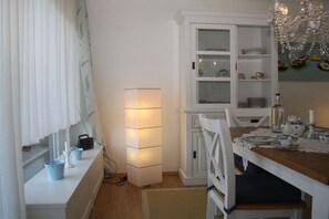 Ein Essbereich mit einem weißen Schrank, einem Tisch mit Tellern und einer Kristallleuchter.