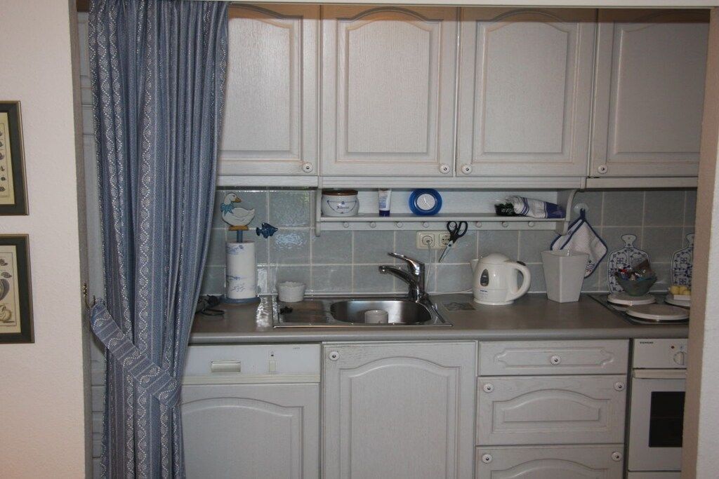 A kitchen with white cabinets, a stainless steel sink, and a microwave.