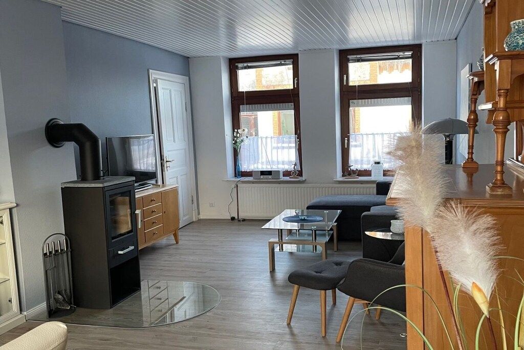 Een moderne woonkamer met een open haard, een bank, een salontafel en een eethoek met een houten tafel en stoelen.