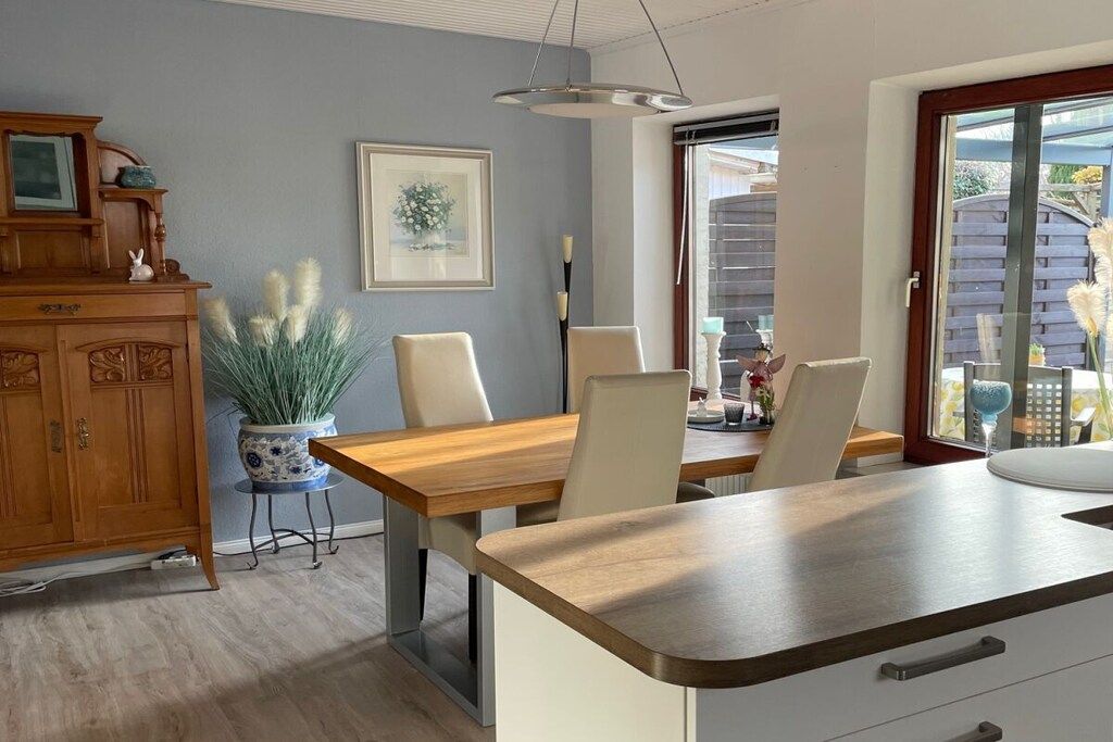 A dining area with a wooden table and chairs, a potted plant, and a cabinet.