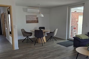 Ein modernes Interieur mit Essbereich, einer Couch und Blick ins Freie.