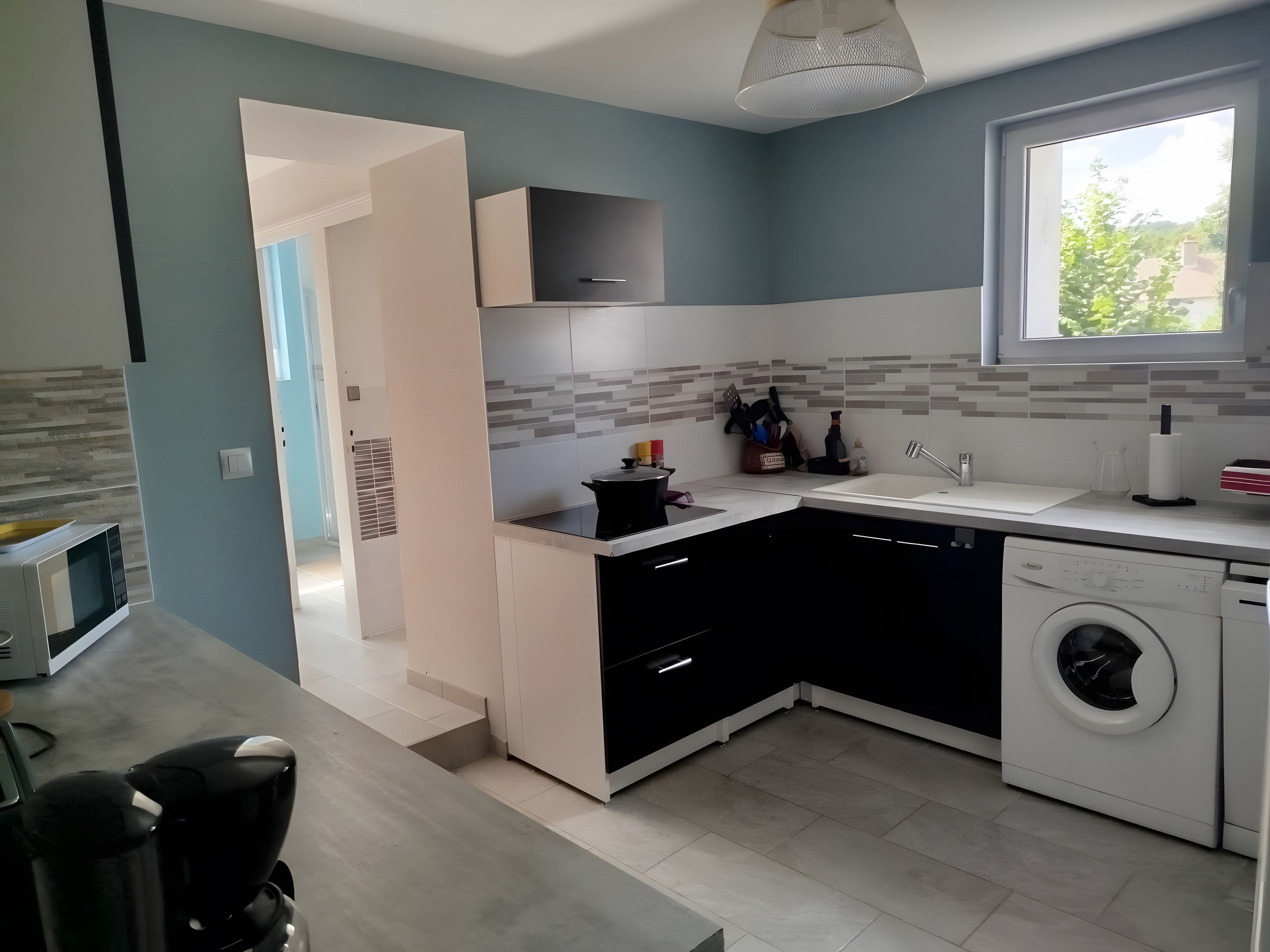Una cocina moderna con microondas, lavaplatos y lavadora.