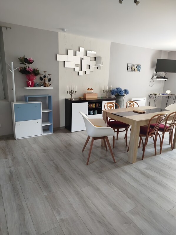 A modern dining area with a wooden table and chairs, a blue and white cabinet, and a wall-mounted light fixture.