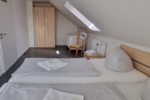 A bedroom with two beds, a wooden wardrobe, a chair, a bedside table, and a skylight. - Wismar cog starboard (Zierow)