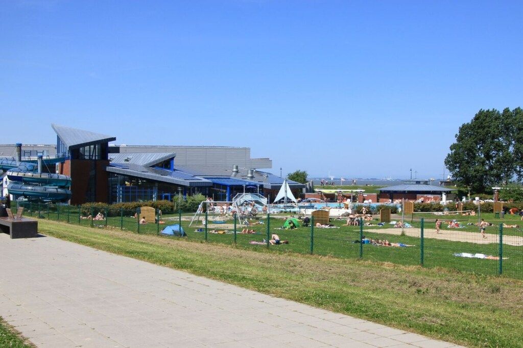 A public park with a swimming pool, a playground, and a building with a modern design.