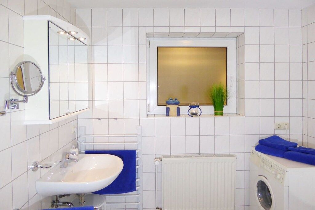 A bathroom with a sink, mirror, window, and a washing machine.