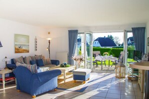 A living room with a sofa, a coffee table, and a view of the garden through a glass door. - Holiday apartment with 1 bedroom (Lindaunis)