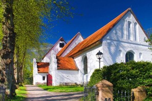 A white building with a red roof, a pathway leading to it, and a stone gate. - Holiday apartment with 1 bedroom (Lindaunis)